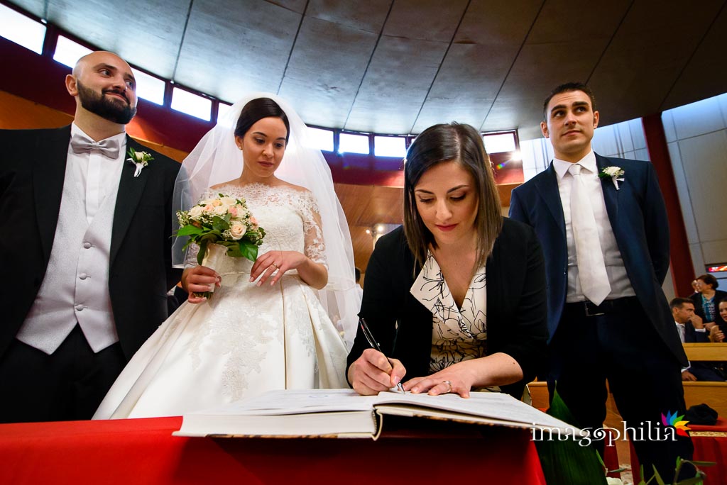 La testimone della sposa firma il registro accanto all'altro testimone