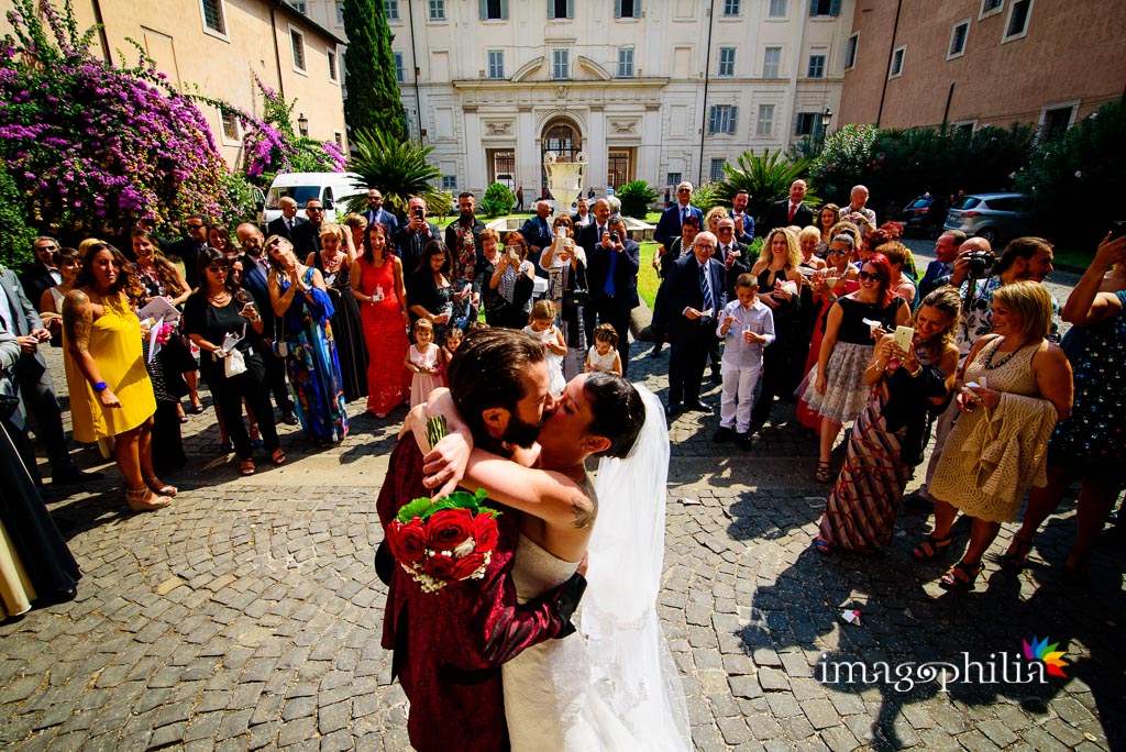 Bacio tra gli sposi dopo il lancio del riso nel chiostro della Basilica di Santa Cecilia in Trastevere a Roma
