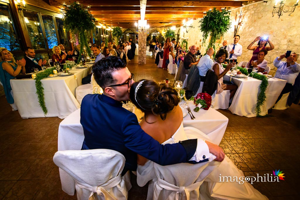 Bacio tra gli sposi con l'intera sala gremita durante il ricevimento di matrimonio presso la Rocca dei Cavalieri di Casaprota