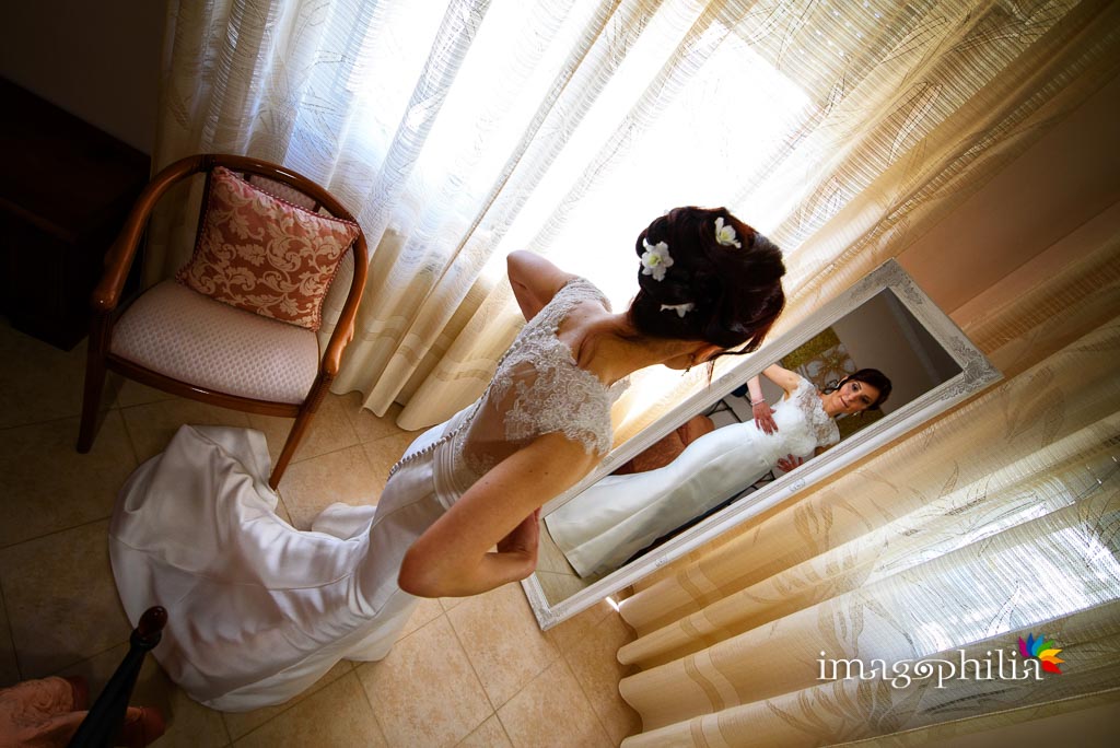 La sposa si guarda allo specchio al termine della preparazione a casa